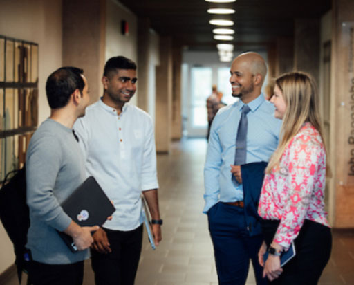 Students talking with professor in hallway.