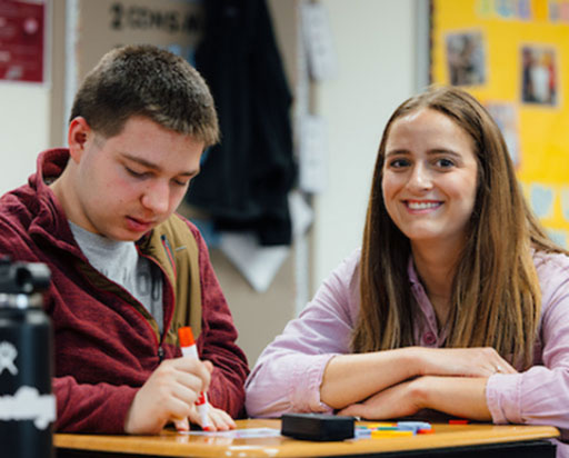 Two students sitting at a desk working on an assignment.