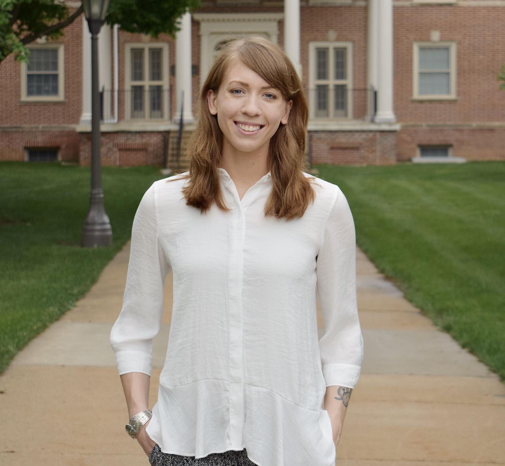 Shelby standing in front of a brick campus building