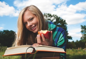 Girl reading book and eating an apple