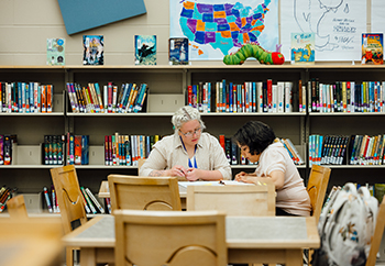 Teacher and student working at a table in the library