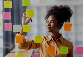 Woman working on post-it notes on wall