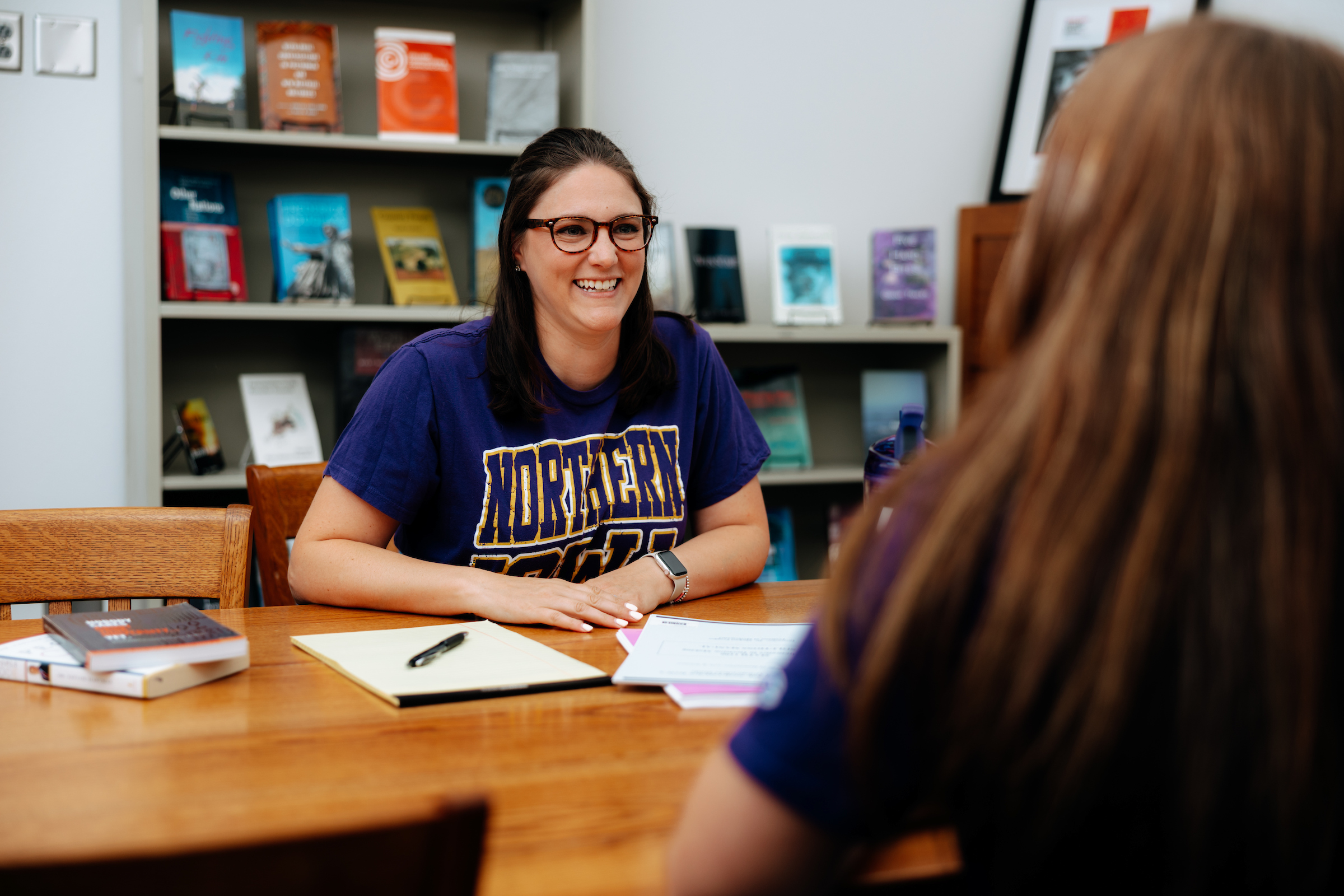 Teacher sitting at desk talking with student