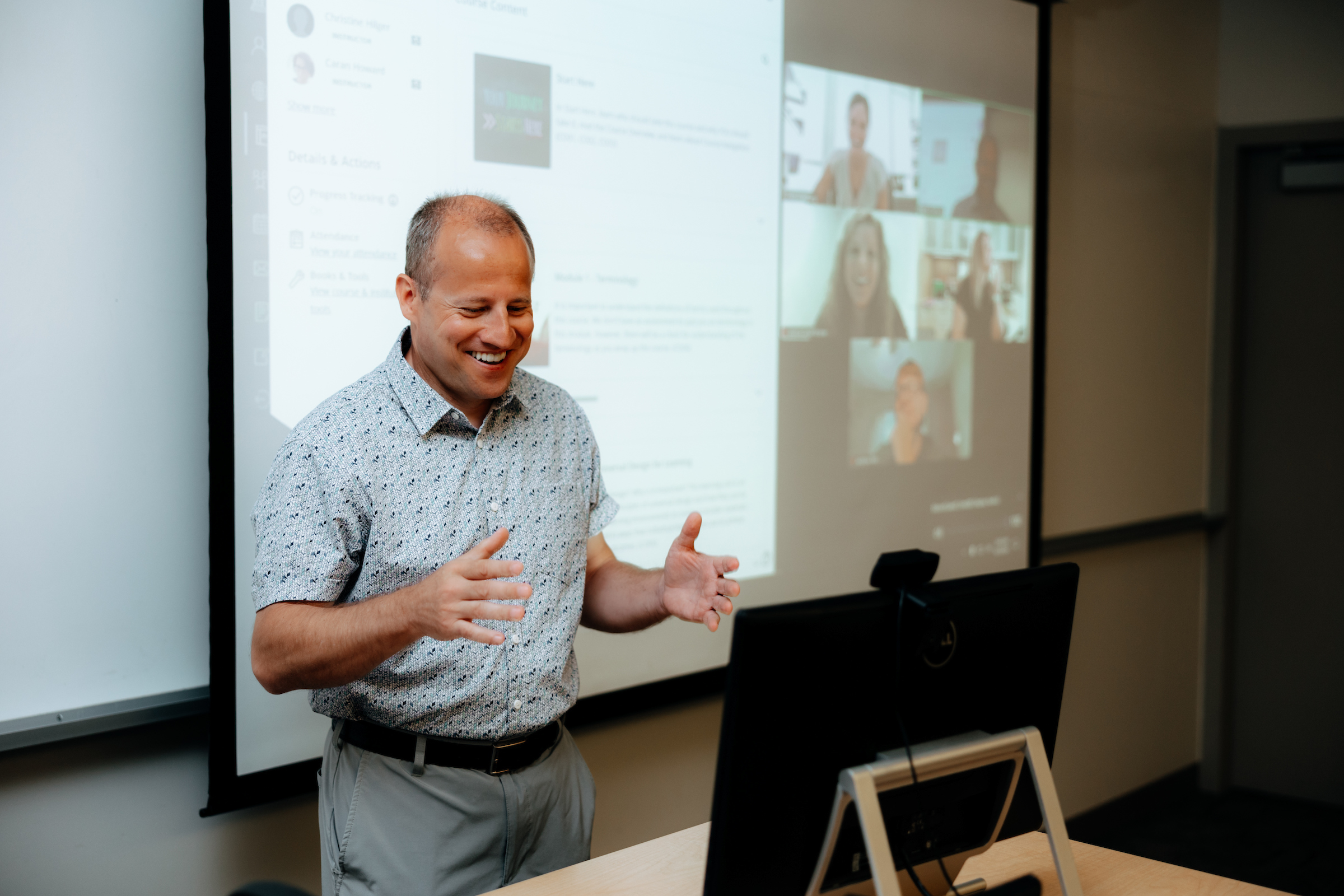 Teacher standing in front of computer teaching online course via zoom.