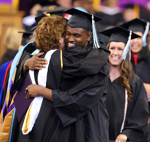 Smiling graduate hugging someone at graduation ceremony