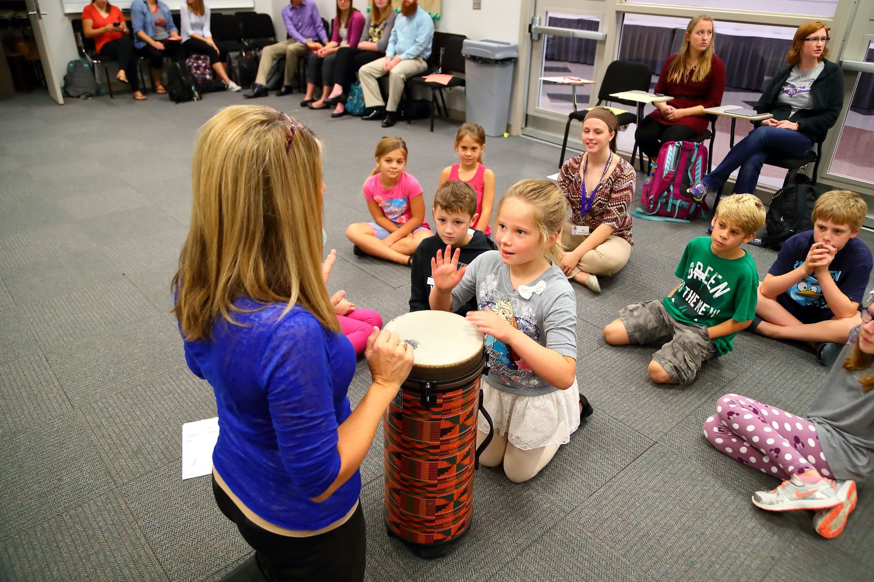 music teacher working with a young female student with a bongo drum