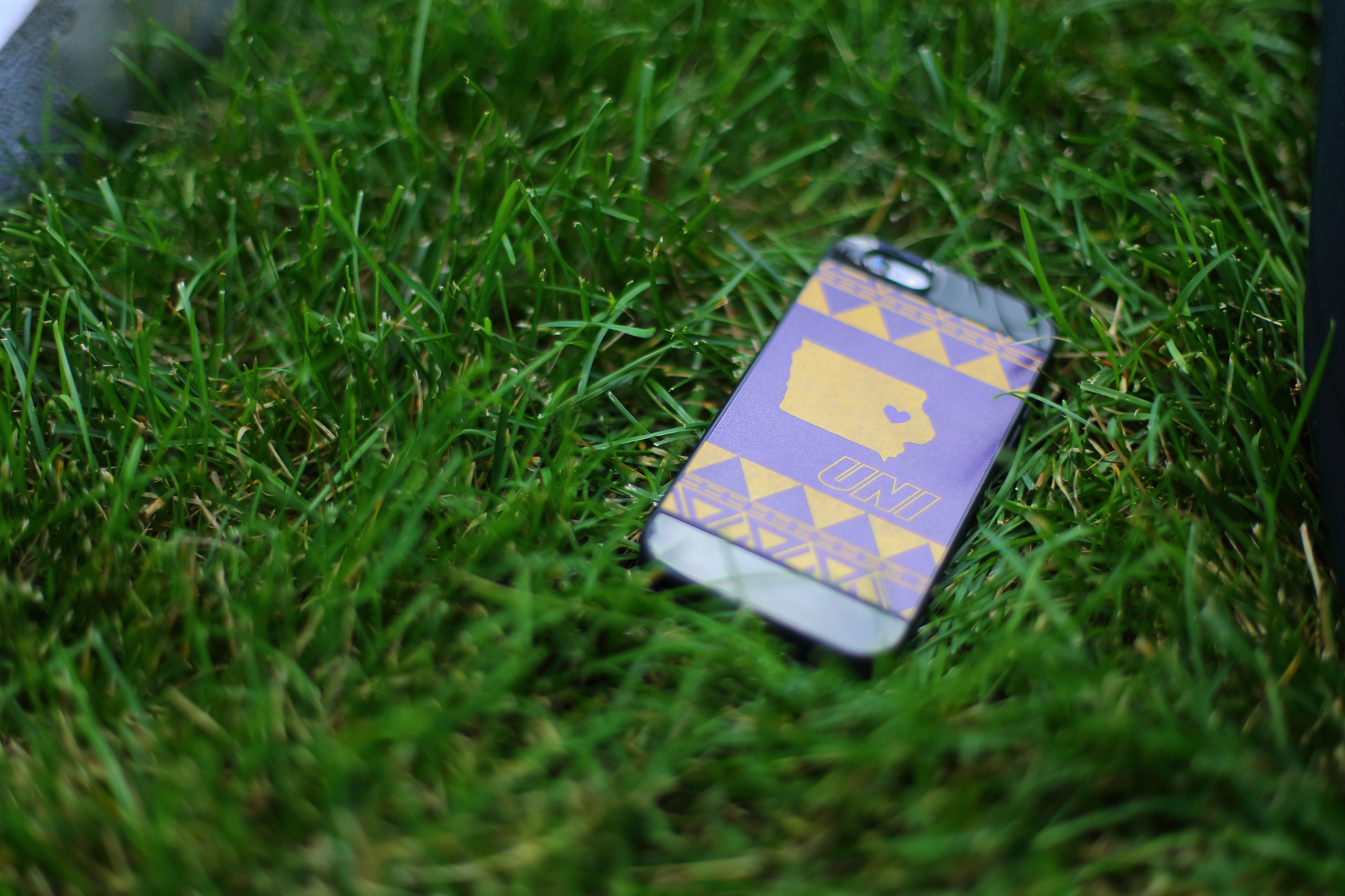 Cell phone with UNI case laying in the grass