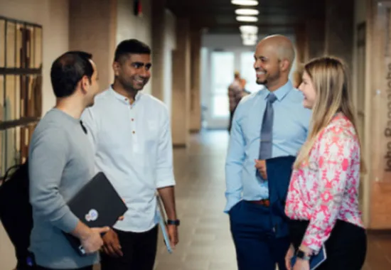 Students talking with professor in hallway.