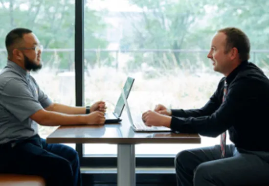 Two people discussing at table.