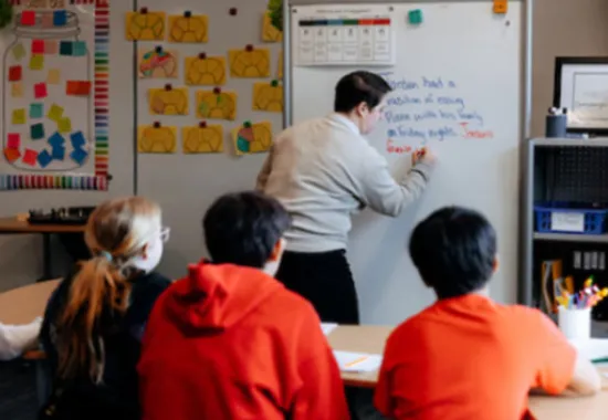 Teacher at the white board teaching students.