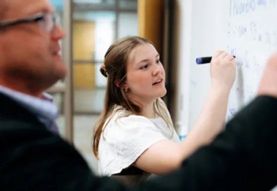 Student writing on whiteboard.