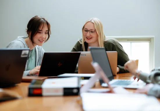 two students working on laptops together