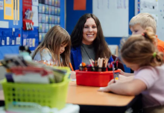 Elementary Education teacher smiling, working with students
