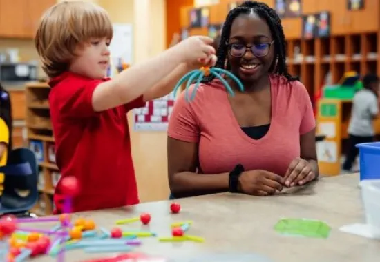 Teacher and student playing with building toys.